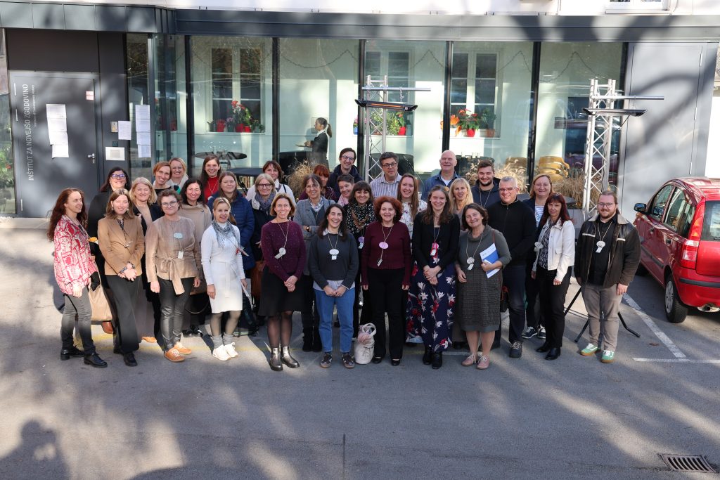 skupinska fotografija udeležencev konference, ki stojijo zunaj pred stavbo
