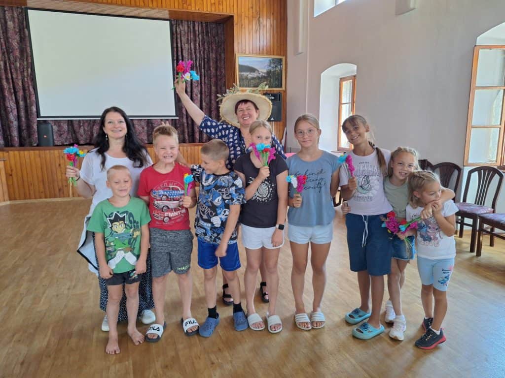 Skupina otrok prikazuje svoje izdelke travniških rož iz papirja